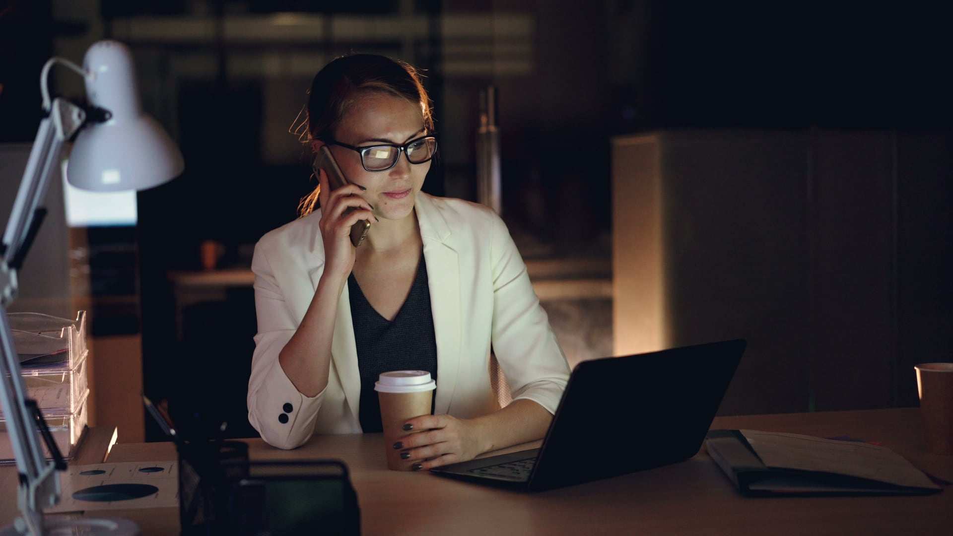 Persona hablando por teléfono frente a una computadora portátil