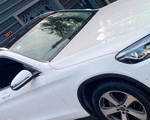 Después: Mercedes-Benz blanca con la puerta rayada y hundida, y la misma puerta reparada y pintada