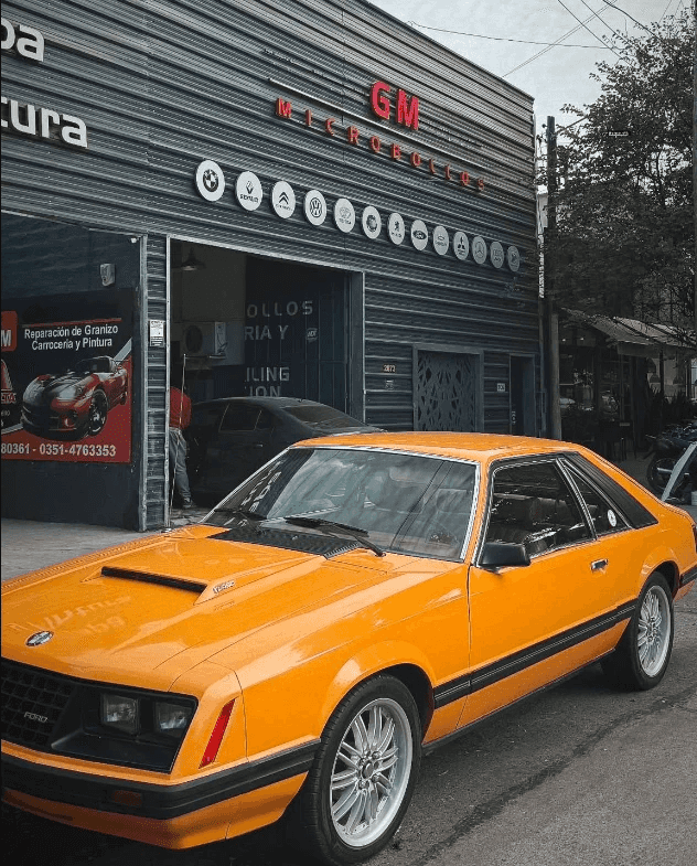 Ford Mustang naranja estacionado frente al portón de Taller GM